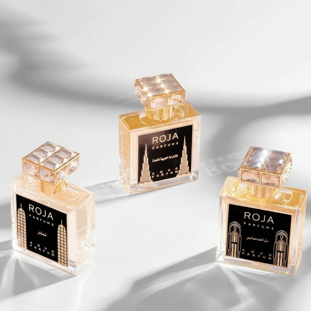 Three ROJA Parfums bottles on a pink fabric background